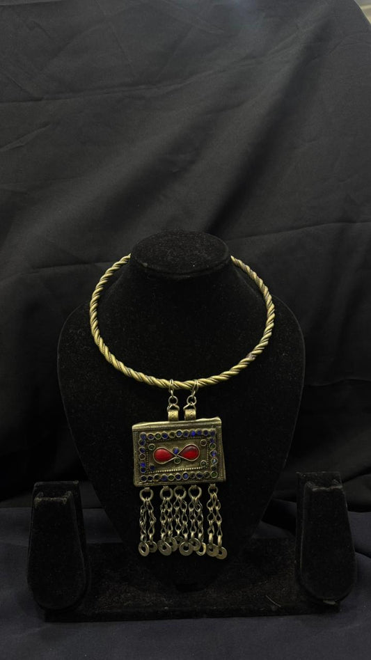 Gold necklace with a pendant on a black stand against a black background